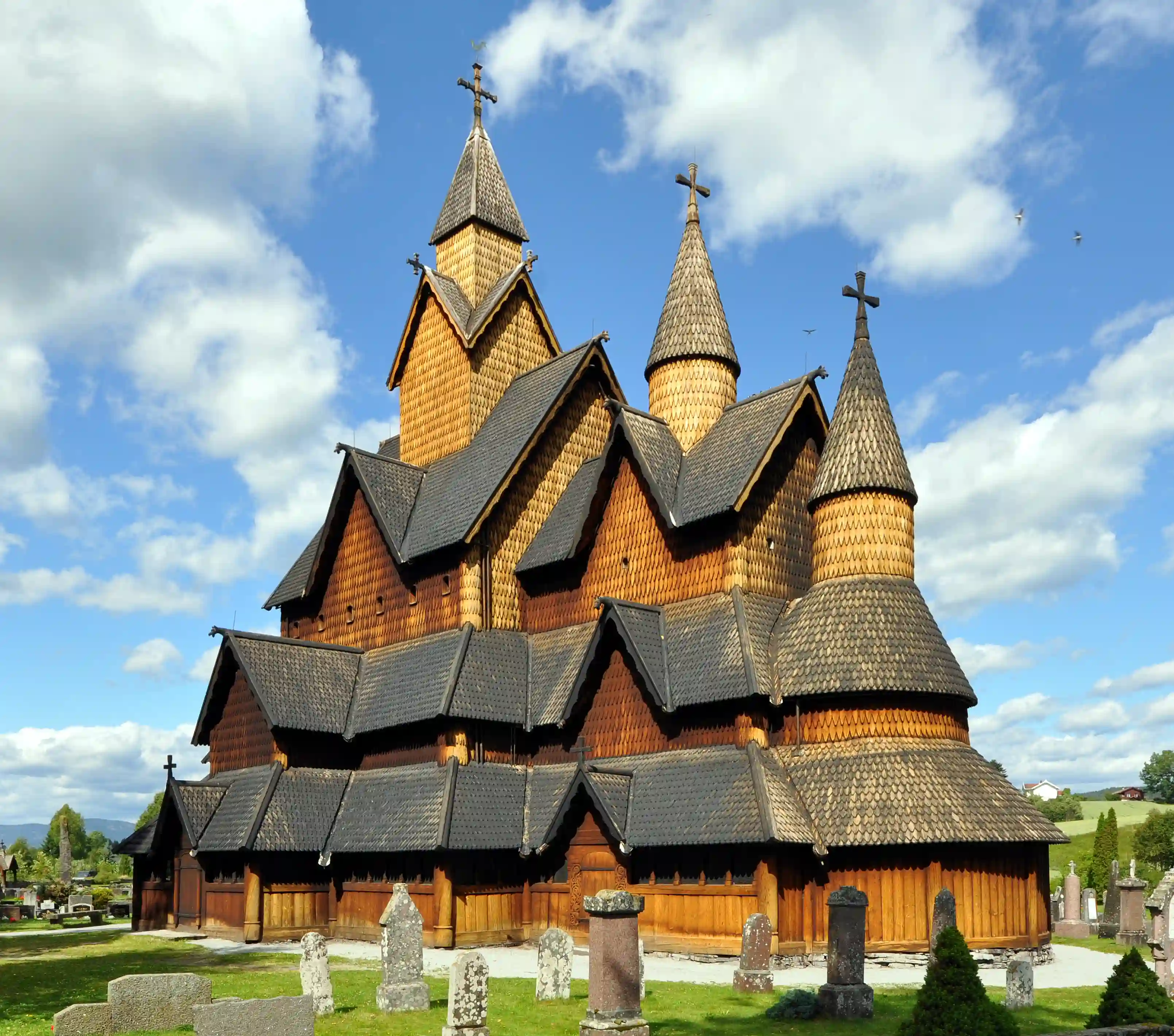 En kirke af træ med sort tag og tre tårne.